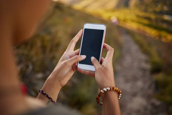 Cada amante de la naturaleza debe descargar esta aplicación. Recorte de una mujer usando su teléfono celular mientras estaba en una caminata. — Foto de Stock