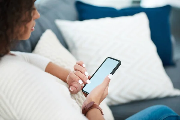 Texto, correo electrónico o llamada, sus opciones son ilimitadas. Fotografía de una mujer joven usando su teléfono celular mientras se relaja en casa. — Foto de Stock