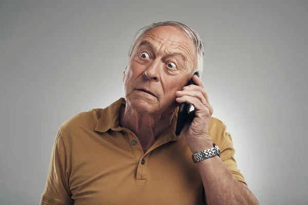 Zeg dat nog eens. Studio shot van een oudere man met behulp van zijn mobiele telefoon tegen een grijze achtergrond. — Stockfoto