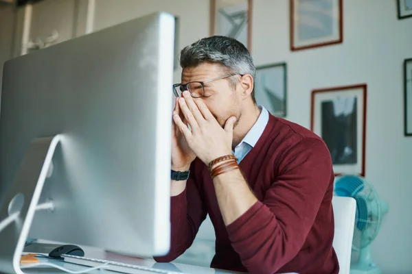 O dia está a tornar-se uma grande dor de cabeça para ele. Tiro de um homem de negócios maduro olhando estressado enquanto trabalhava em um computador em um escritório. — Fotografia de Stock