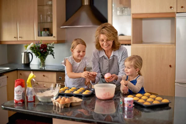 Onlar Cupcake Profesyonelleri. İki küçük kız evde büyükannelerinin yardımıyla kek pişiriyor.. — Stok fotoğraf