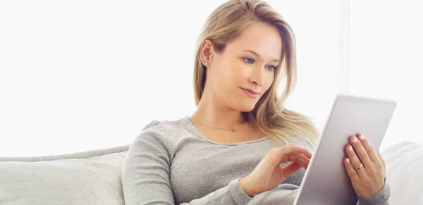 Descubrir nueva información se ha vuelto tan eficiente. Fotografía de una joven atractiva usando una tableta en casa. —  Fotos de Stock