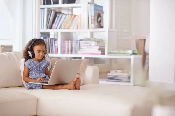 Conseguir que aprenda. Foto de una niña pequeña usando auriculares y una computadora portátil mientras está sentada en casa. — Foto de Stock