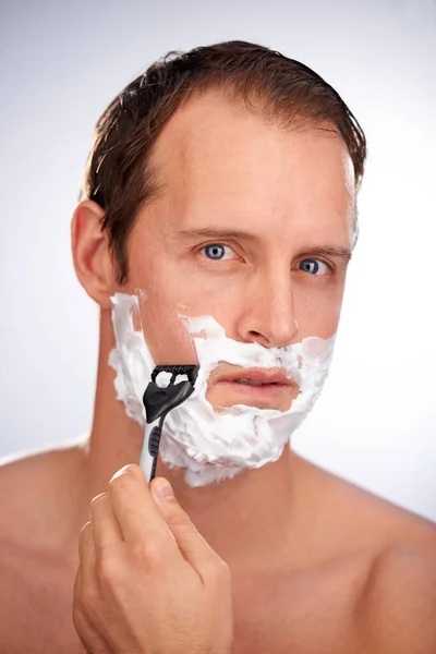 Shaving himself from a hairy situation. Studio shot of a man concentrating on shaving. — Stock Photo, Image