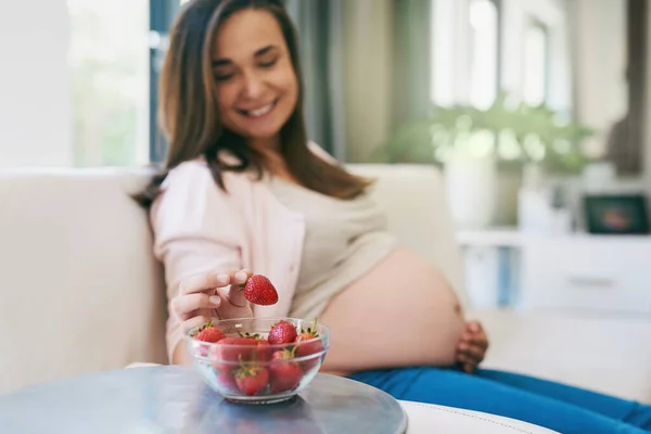 Zdravý jako řípa. Shot těhotné ženy svačinka na jahody. — Stock fotografie