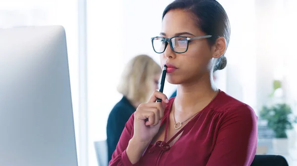 Je dois prendre une minute pour y réfléchir. Plan recadré d'une jeune femme d'affaires concentrée travaillant sur son ordinateur tout en contemplant l'intérieur du bureau. — Photo