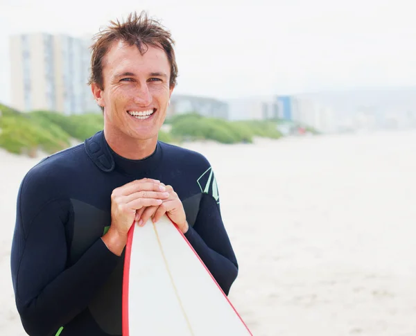 Sentindo-se bem depois de uma sessão épica. Um surfista posando na praia com sua prancha ao lado do copyspace. — Fotografia de Stock