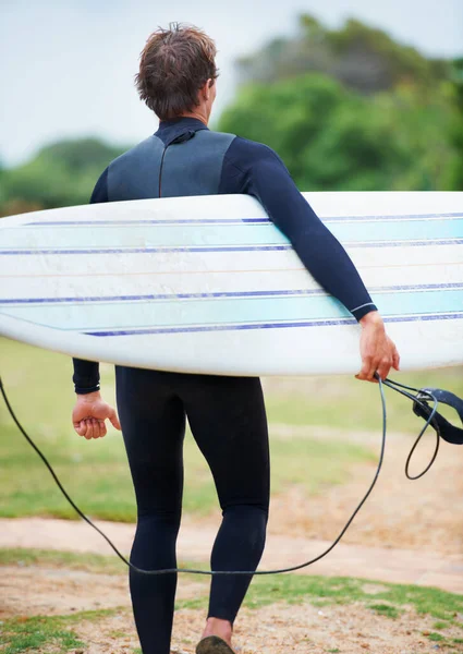 A szörfözés egy életstílus. Egy szörfös vitte a deszkáját a partra menet.. — Stock Fotó