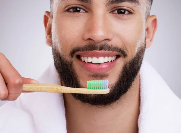 N'oubliez pas d'utiliser des mouvements circulaires. Tourné d'un beau jeune homme se brossant les dents sur un fond de studio. — Photo