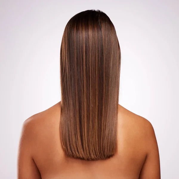 Идеально слоистый. Студийный снимок неузнаваемой молодой женщины, стоящей спиной к камере, чтобы показать свои волосы на сером фоне. — стоковое фото