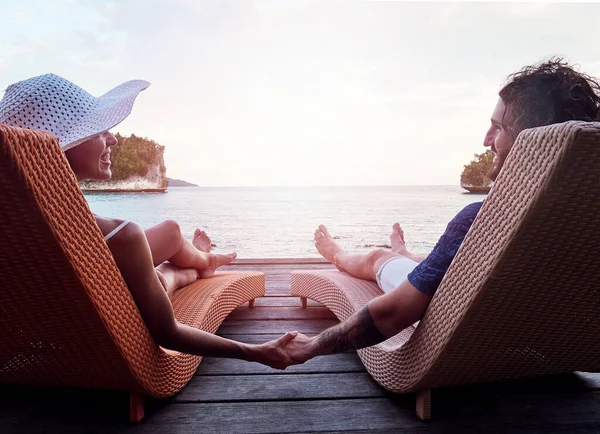 Só nós os dois. Rearview tiro de um jovem casal alegre de mãos dadas enquanto relaxa em cadeiras de convés e olhando para o oceano fora durante o dia. — Fotografia de Stock