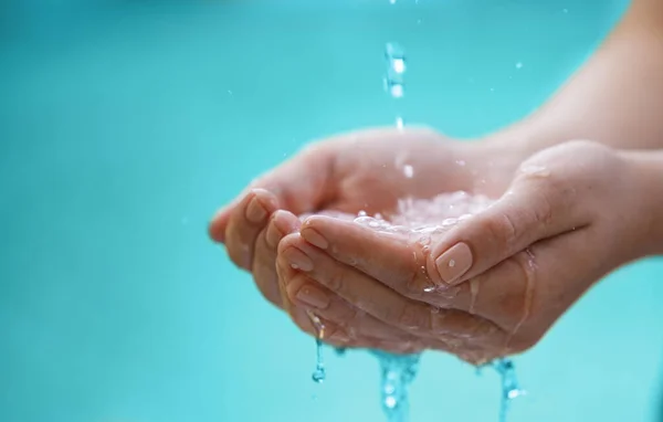 Fräscha upp törsten med lite sötvatten. Beskärda skott av vatten som rinner på händerna på en oigenkännlig person. — Stockfoto