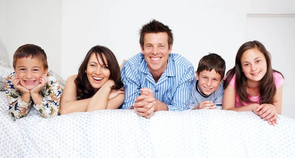 Dohoní mě to na konci dne. Milující pětičlenná rodina ležící spolu v posteli v pyžamu.. — Stock fotografie