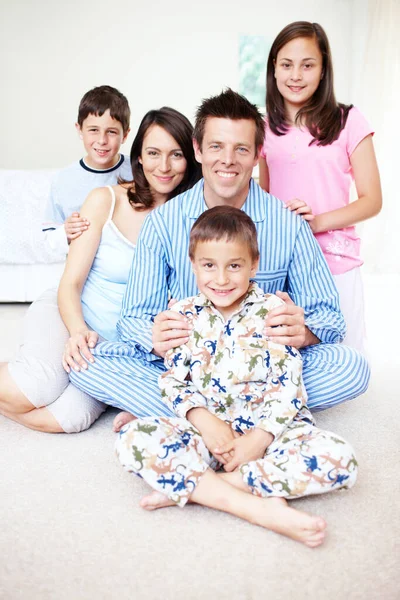 Vroege mensen op zaterdagochtend. Portret van een schattig jongetje met zijn gezin achter hem gelukkig op een bed. — Stockfoto