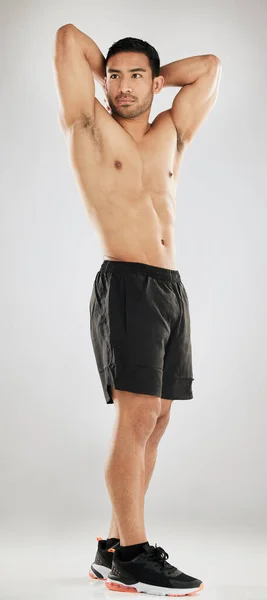 You gotta love a muscular stud. Studio shot of a handsome young man showing off his muscular body while posing against a grey background. — Stock Photo, Image