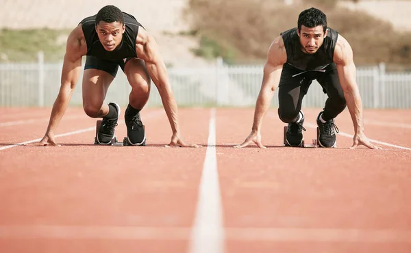 Listo para empezar. Largura completa de tiro de dos guapos jóvenes atletas masculinos comenzando su carrera en una pista. — Foto de Stock