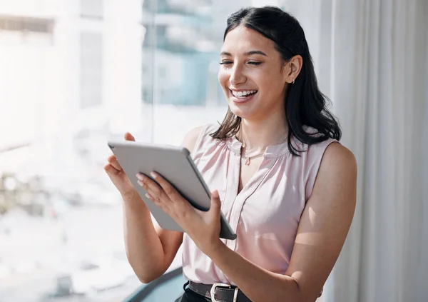 La tecnología facilita la carga de trabajo. Fotografía de una atractiva joven empresaria parada sola en la oficina y utilizando una tableta digital. —  Fotos de Stock