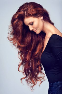 Devam et, saçlarını sal. Gri bir arka planda poz veren güzel kızıl saçlı genç bir kadının stüdyo fotoğrafı..