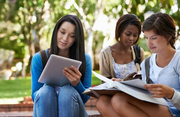 Tekniken gör det lättare att studera. Skjuten av en skiftande grupp collegestudenter sitter tillsammans utanför gör online-forskning. — Stockfoto