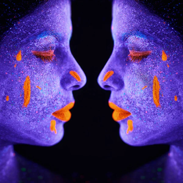 Irmãs em simetria. Espelho tiro de uma jovem posando com tinta de néon em seu rosto. — Fotografia de Stock