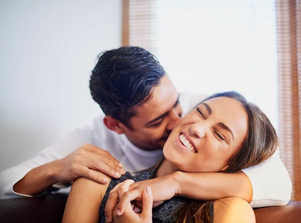 El amor está en el aire. Foto de una joven pareja riéndose compartiendo un momento juntos en casa. — Foto de Stock