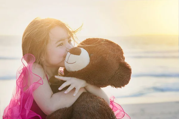 La inocencia de la infancia. Retrato de una linda niña jugando con su osito de peluche en la playa. —  Fotos de Stock