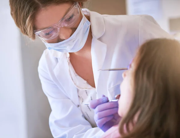 Il mio obiettivo è quello di fornire cure eccezionali per il vostro bambino. Colpo ritagliato di un dentista che esamina i denti di una bambina. — Foto Stock