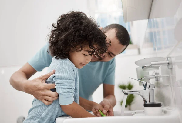 Vyčistíme teď a pak později večer znovu. Zastřelen otec pomáhá svému synovi vypláchnout si kartáček na zuby, zatímco si čistí zuby doma v koupelně. — Stock fotografie