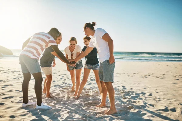 Beloof me dat je van deze zomer de beste tot nu toe maakt. Schot van een groep jongeren die hun handen samenvoegen in solidariteit op het strand. — Stockfoto