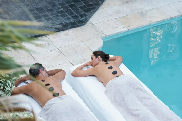 Synchrone Harmonie im Luxus. Hochwinkelaufnahme eines Paares, das eine Hot Stone Massage genießt. — Stockfoto