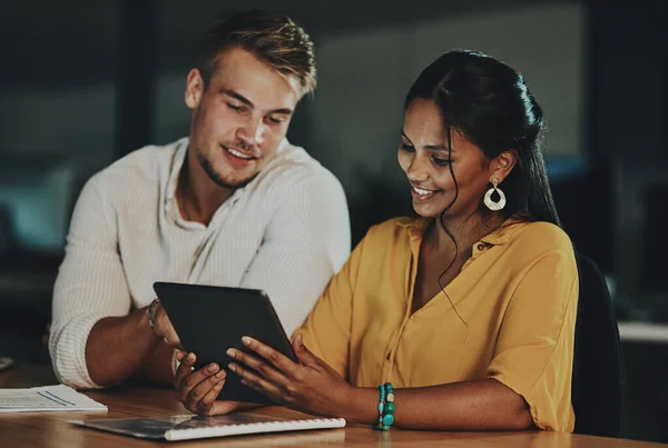 De wereld online zal hen in staat stellen om de deadline te halen. Opname van twee zakenmensen die 's nachts samen in een kantoor een digitale tablet gebruiken. — Stockfoto