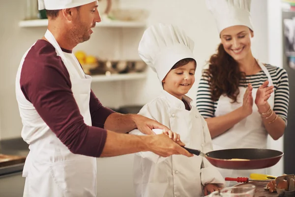 Οικογενειακή διασκέδαση στην κουζίνα. Μια χαμογελαστή οικογένεια φτιάχνει τηγανίτες μαζί στην κουζίνα.. — Φωτογραφία Αρχείου