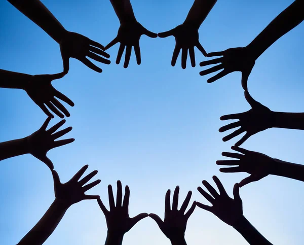 Anything is possible if we do it together. Low angle shot of hands forming a circle against a bright blue sky. — Stock Photo, Image