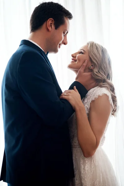 Youre the most angelic being I have ever seen. Cropped shot of a happy young couple standing indoors and holding each other affectionately after their wedding. — Stock Photo, Image