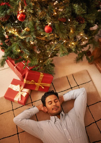 Warten auf den Weihnachtsmann. Aufnahme eines jungen Mannes, der unter dem Weihnachtsbaum schläft. — Stockfoto