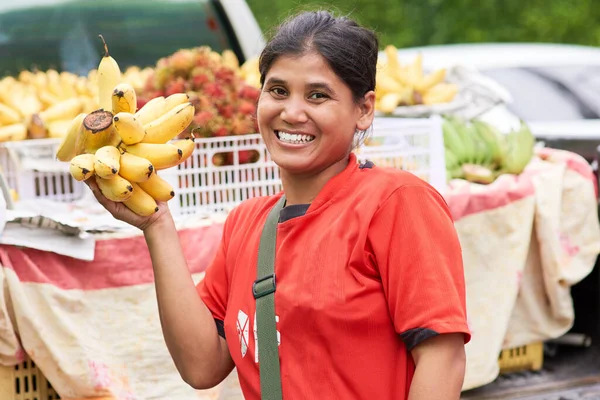 我只卖最新鲜的农产品.一个女人在外面的市场摊位卖香蕉的画像. — 图库照片