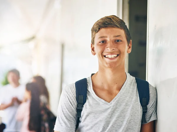 Мое будущее выглядит светлым. Портрет счастливого школьника, стоящего вне класса с одноклассниками на заднем плане. — стоковое фото
