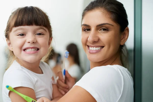 All minty fresh. Portrait of a mother and daughter brushing their teeth together in the bathroom at home. — Stock Photo, Image