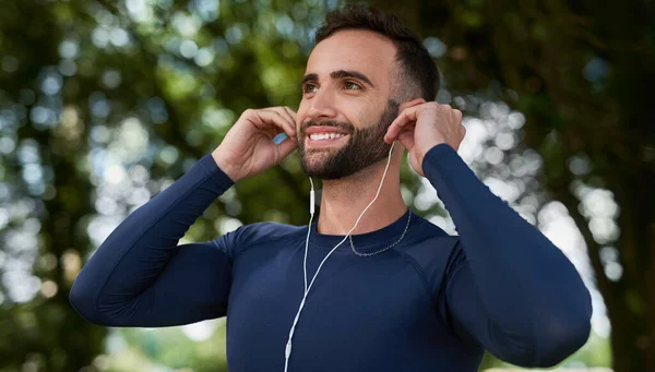 Ahora hay una canción con la que puedo trabajar. Recortado disparo de un joven corredor guapo escuchando música durante su entrenamiento. — Foto de Stock