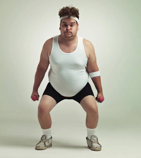 Deep squat. Portrait of an overweight man squatting and lifting dumbbells. — Stock Photo, Image