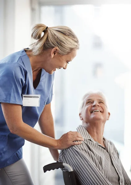 Vart ska vi, herrn? Beskuren bild av en mogen kvinnlig sjuksköterska och hennes äldre manliga rullstolsbundna patient på sjukhuset. — Stockfoto