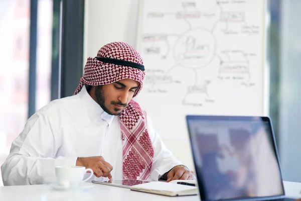 Mit intelligenter Technologie am Ball bleiben. Aufnahme eines jungen muslimischen Geschäftsmannes mit einem digitalen Tablet an seinem Schreibtisch. — Stockfoto