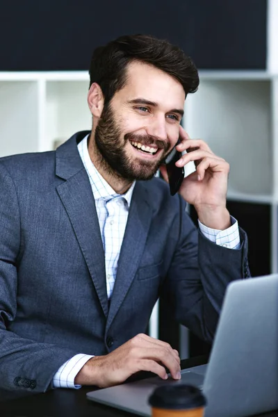 Me alegro de haber sido de ayuda. Recorte de un joven hombre de negocios hablando en un teléfono celular mientras trabajaba en una computadora portátil en una oficina moderna. — Foto de Stock
