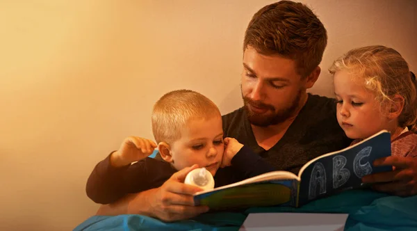 Et puis ils ont vécu heureux pour toujours... Un père lisant une histoire au lit à ses enfants. — Photo