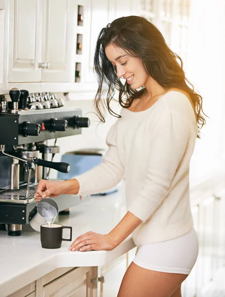 Jej dzień zaczyna się od kremowego cappuccino. Strzał młodej kobiety parzącej kawę w kuchni. — Zdjęcie stockowe
