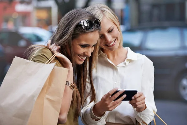 그 방향을 저장 합니다. 두 젊은 여자가 쇼핑백을 들고 밖에서 서 문자를 보내고 있다. — 스톡 사진