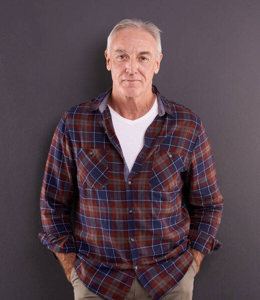 Content with life. Studio portrait of an elderly man against a gray background.