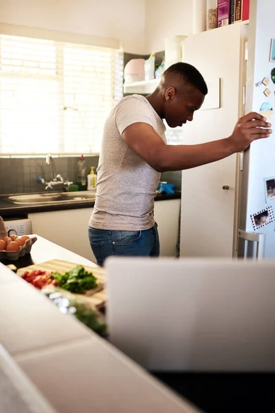 Νιώθω σαν να μου λείπει κάτι... τραβηγμένο πλάνο ενός όμορφου νεαρού άνδρα που κοιτάζει μέσα στο ψυγείο του ενώ φτιάχνει πρωινό στην κουζίνα του στο σπίτι.. — Φωτογραφία Αρχείου