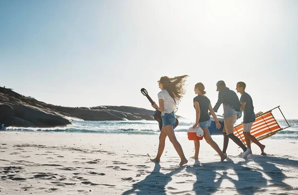 Onnellisuus on rannalle vietetty päivä. Laukaus ryhmä nuoria ystäviä kävelee rannalla aurinkoisena päivänä. — kuvapankkivalokuva