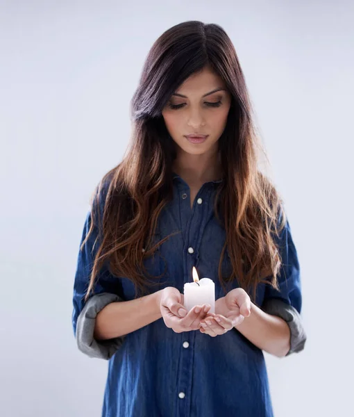 Eine Kerze für den Frieden anzünden. Studioaufnahme einer schönen Frau isoliert auf grauem Hintergrund. — Stockfoto